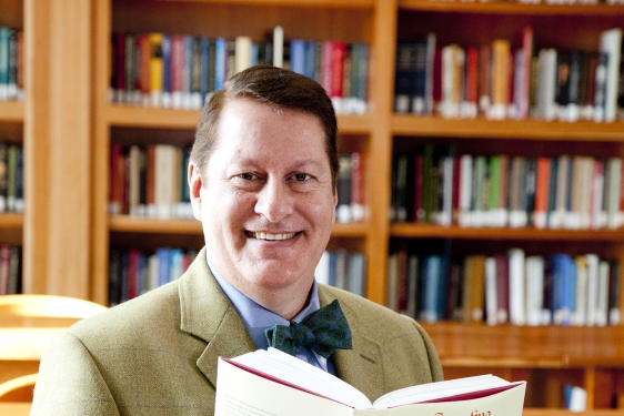 photo of man with book and book shelves
