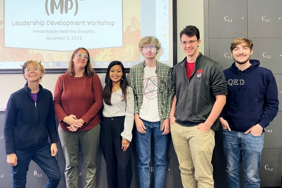 group photo of six people, with projection screen in background